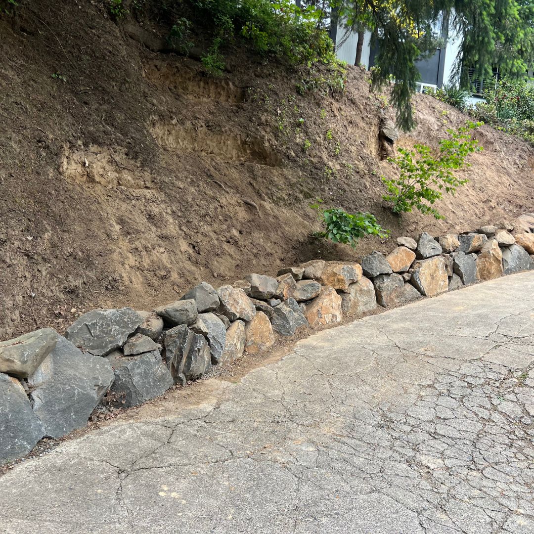 View of pavement meeting dirt wall with rock lining