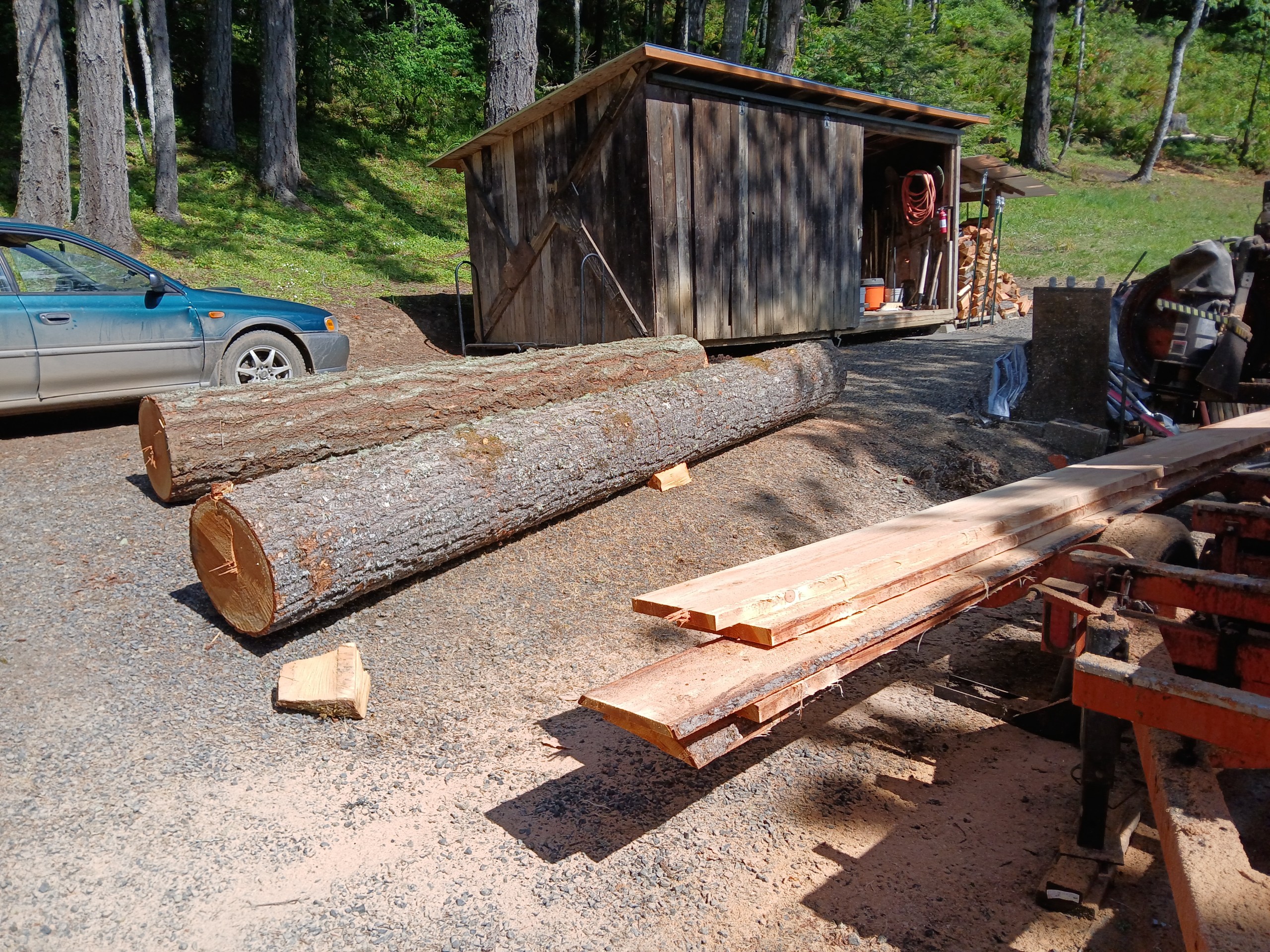 Two logs next to a pile of lumber on the ground