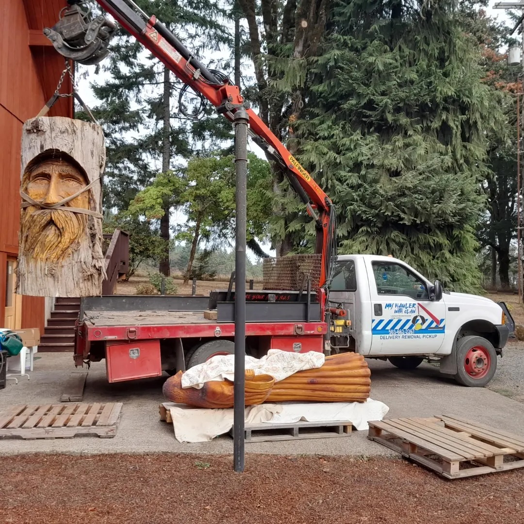 Large wood carving being moved with a grapple truck